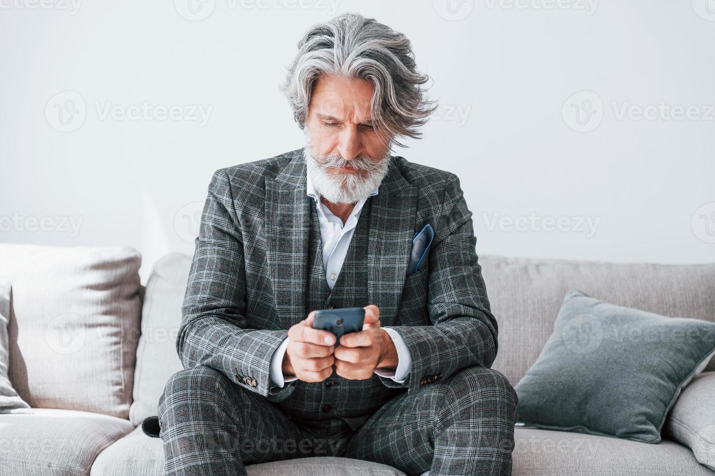 em apartamento com roupas elegantes. homem moderno elegante sênior com cabelos grisalhos e barba dentro de casa foto