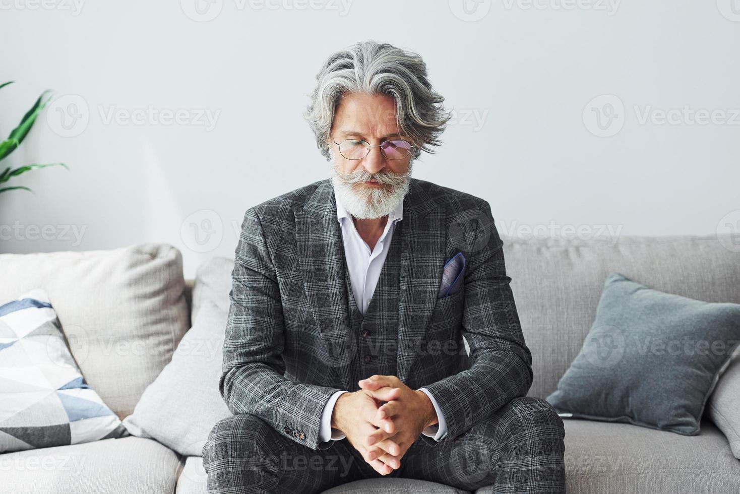 concepção de estilo bonito. homem moderno elegante sênior com cabelos grisalhos e barba dentro de casa foto