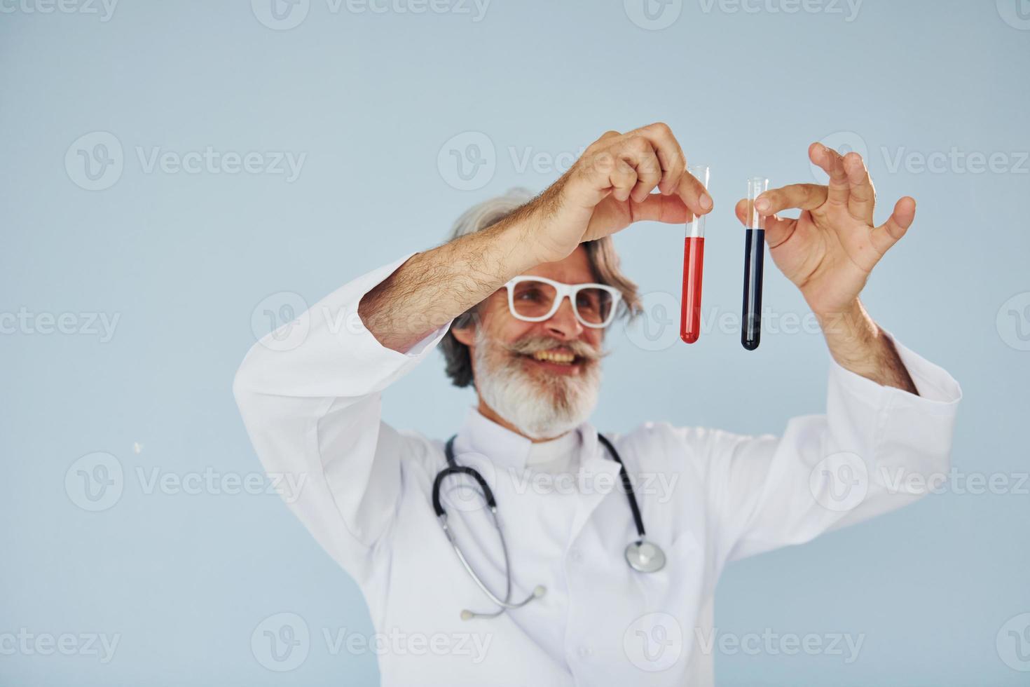 médico detém tubos de ensaio. homem moderno elegante sênior com cabelos grisalhos e barba dentro de casa foto