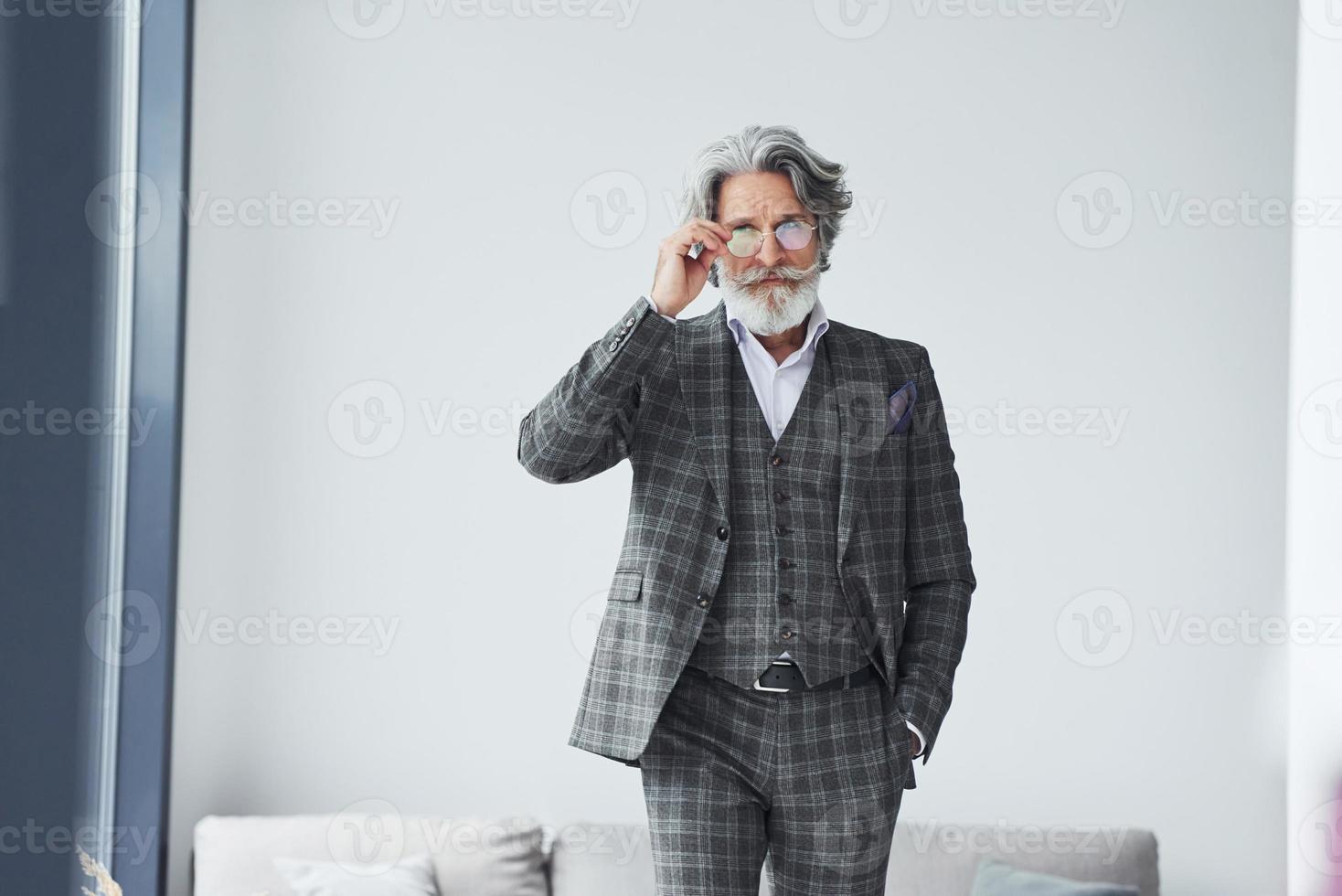 concepção de estilo bonito. homem moderno elegante sênior com cabelos grisalhos e barba dentro de casa foto