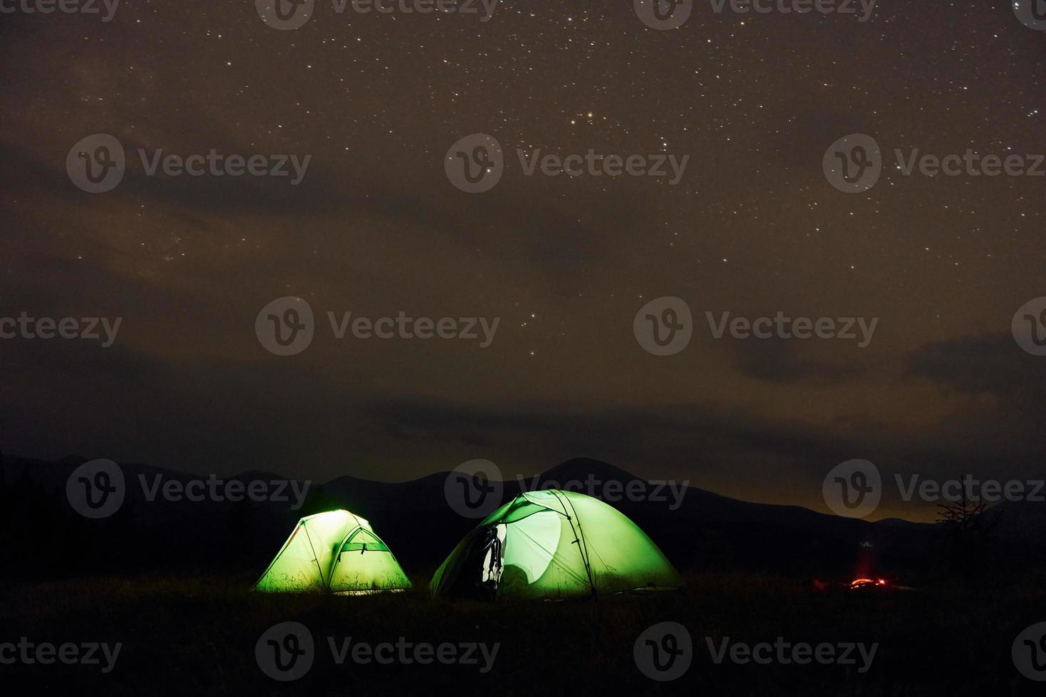 tendas verdes durante a noite. céu estrelado. majestosas montanhas dos cárpatos. bela paisagem de natureza intocada foto