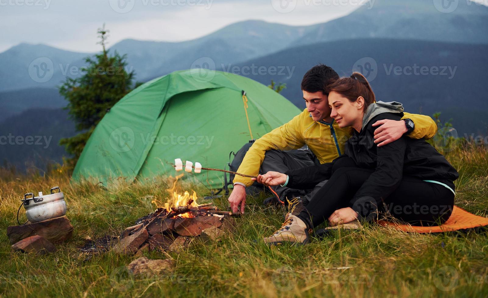 casal com marshmallow perto da fogueira. majestosas montanhas dos cárpatos. bela paisagem de natureza intocada foto