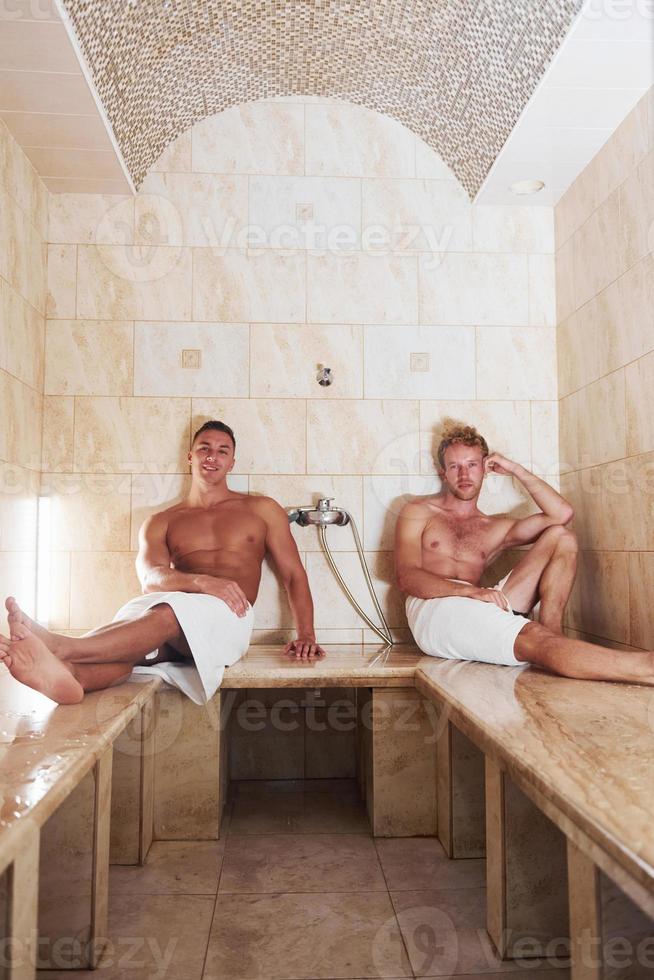 dois amigos do sexo masculino juntos na sauna. concepção de férias e fim de semana foto