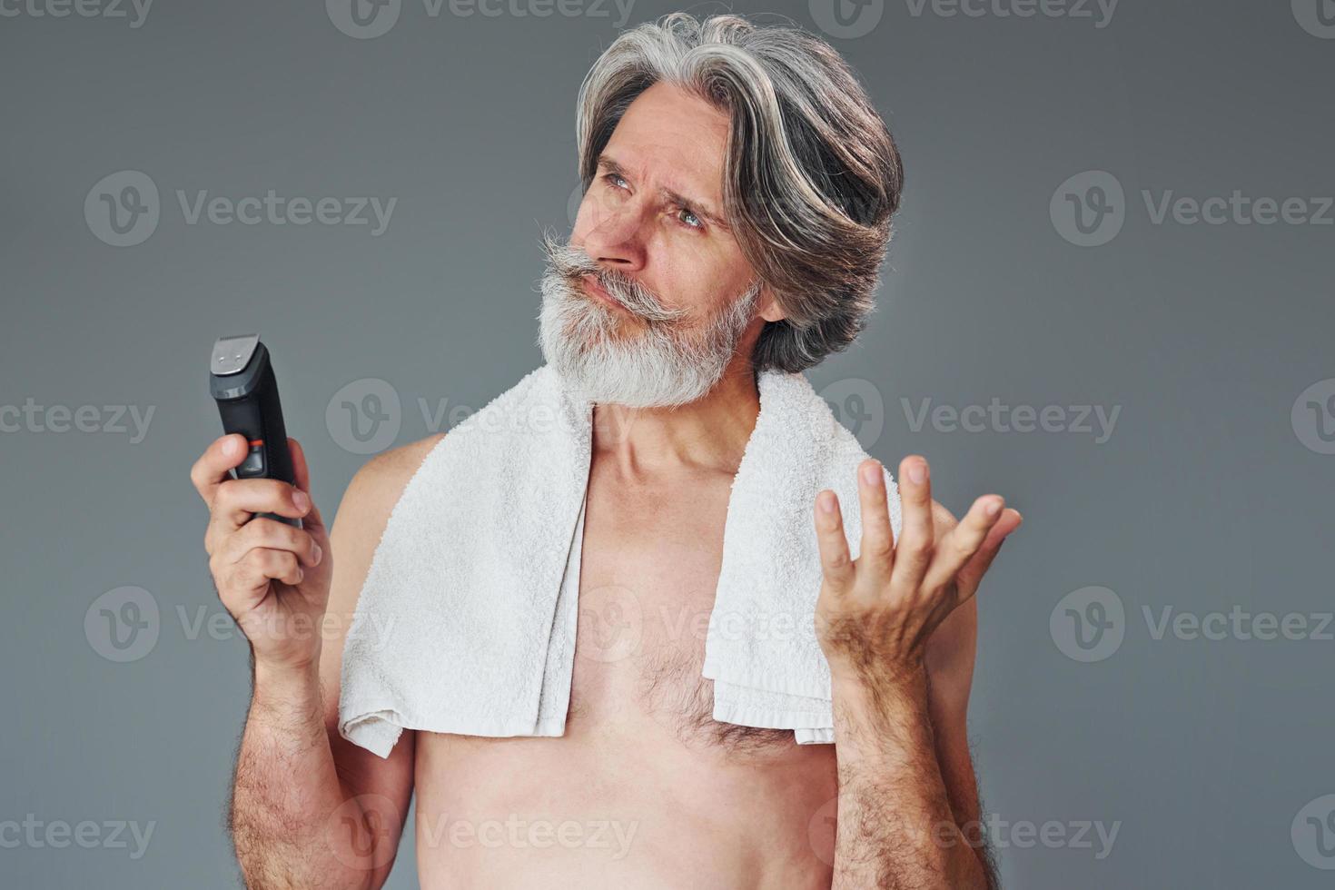 cuidando da barba. elegante homem sênior moderno com cabelos grisalhos está dentro de casa foto