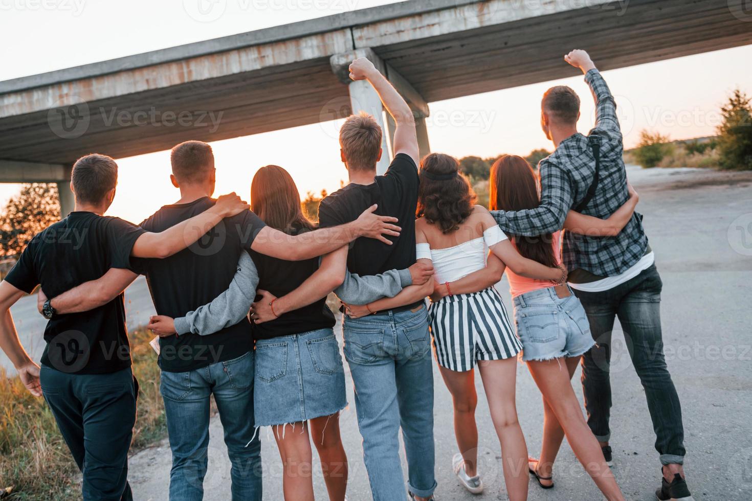 vista de trás. grupo de jovens amigos alegres se divertindo juntos. festa ao ar livre foto