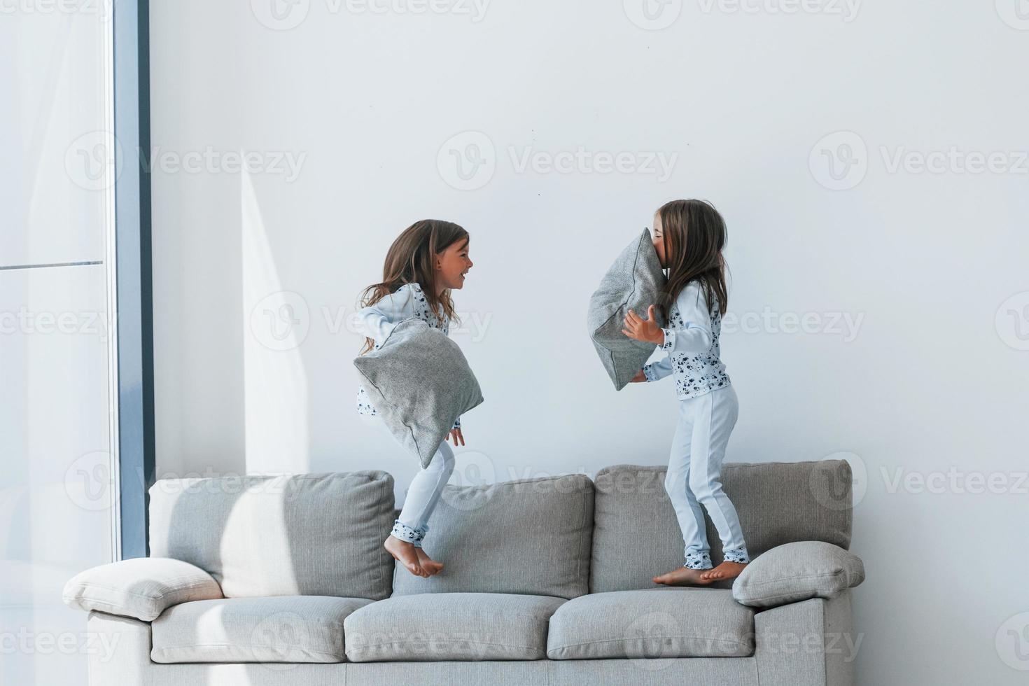 luta de almofadas. duas meninas bonitinhas dentro de casa juntas. crianças se divertindo foto