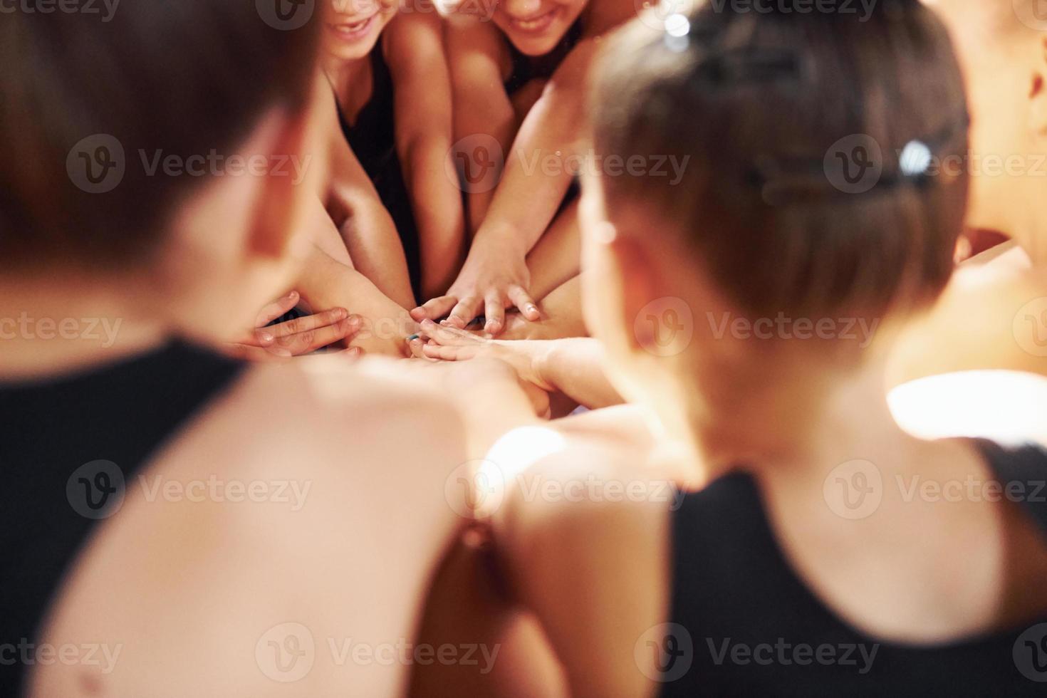 muitas pessoas. grupo de crianças do sexo feminino praticando exercícios atléticos juntos dentro de casa foto