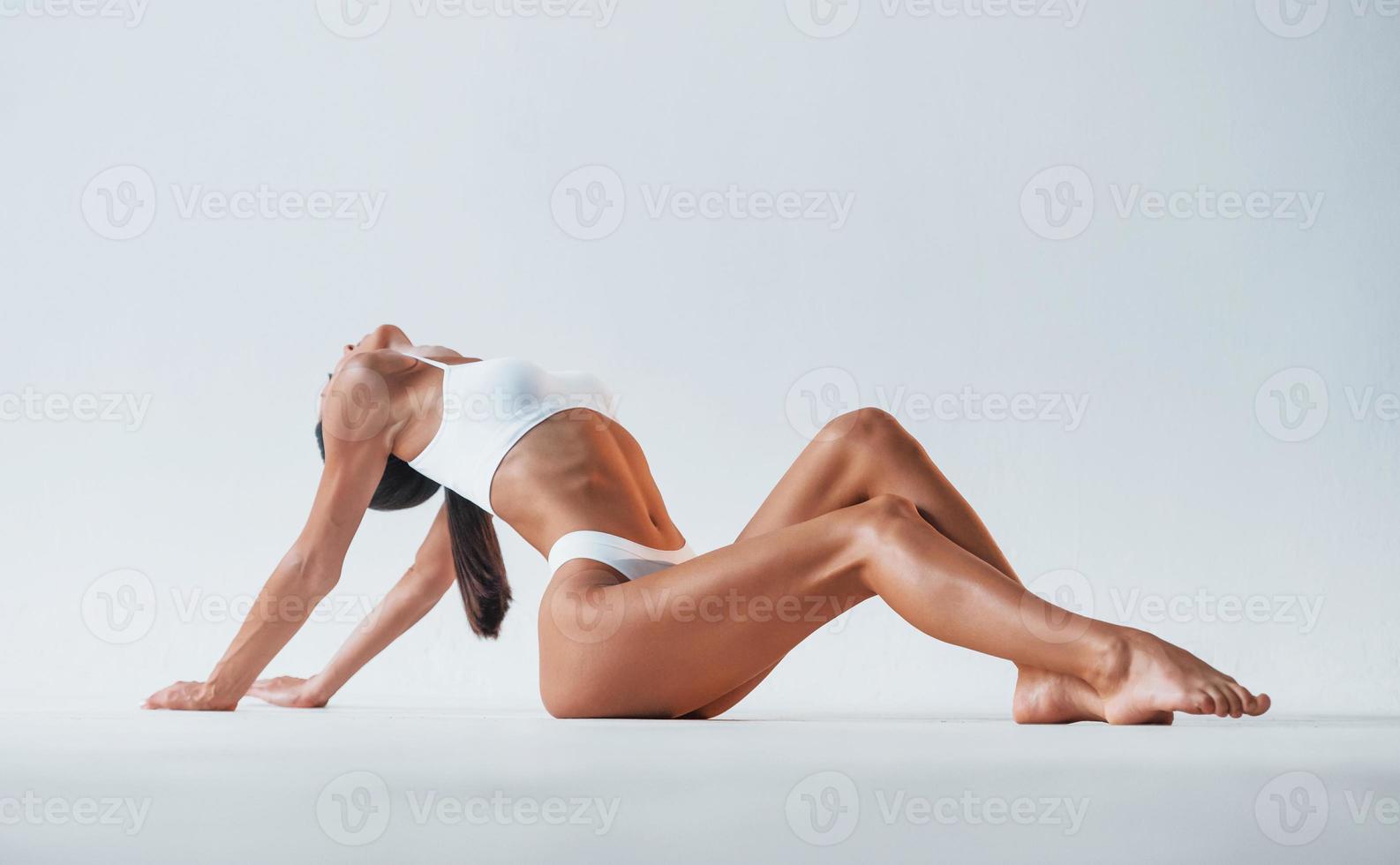sentado no chão. mulher bonita com corpo magro em cueca está no estúdio foto