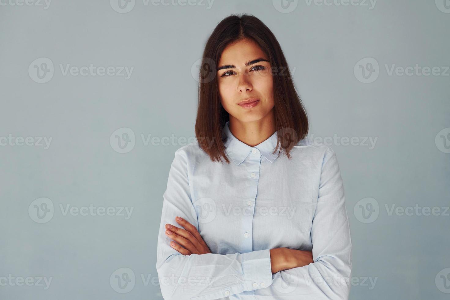 jovem mulher moderna em pé de camisa branca dentro do estúdio foto