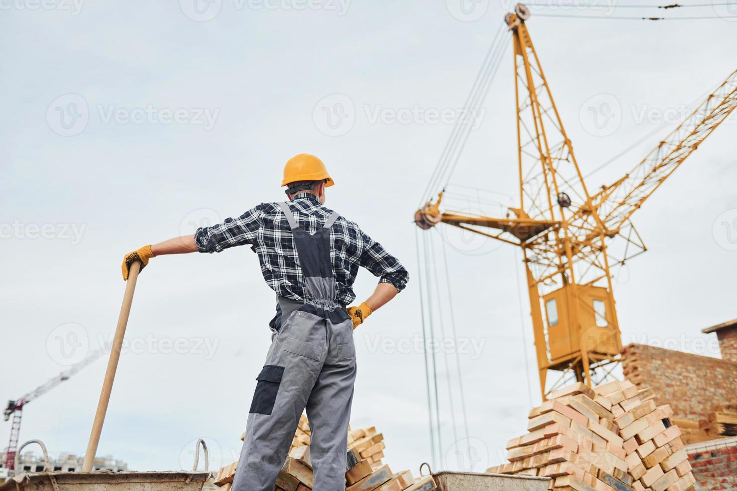 com pá nas mãos. trabalhador da construção civil em equipamentos uniformes e de segurança tem trabalho na construção foto