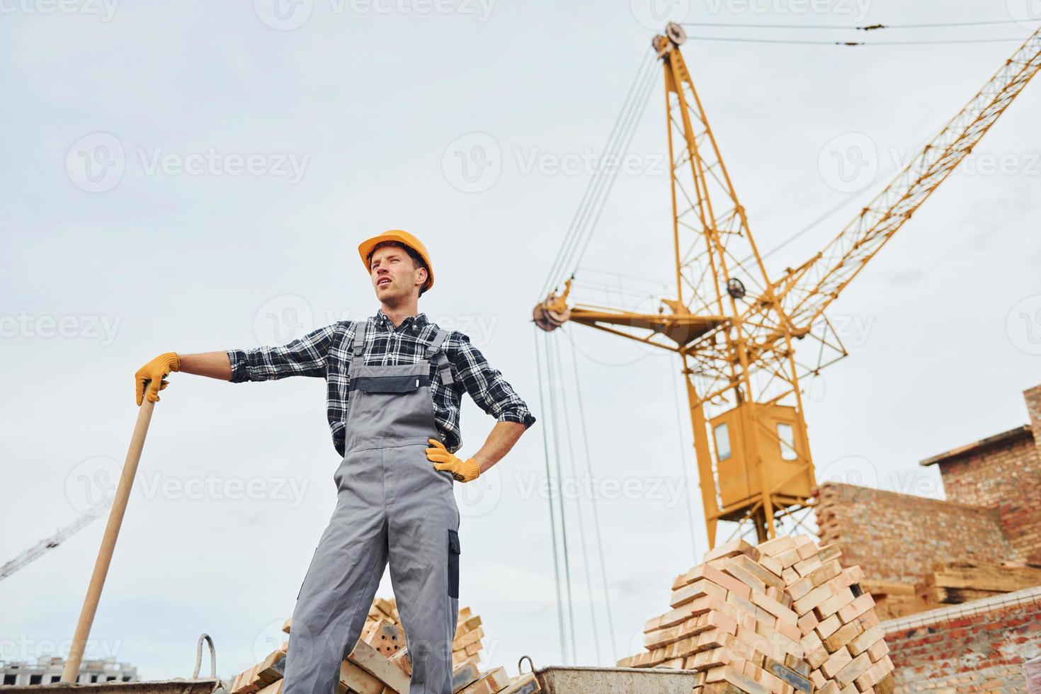 com pá nas mãos. trabalhador da construção civil em equipamentos uniformes e de segurança tem trabalho na construção foto