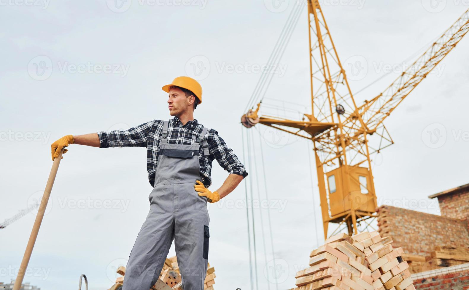 com pá nas mãos. trabalhador da construção civil em equipamentos uniformes e de segurança tem trabalho na construção foto