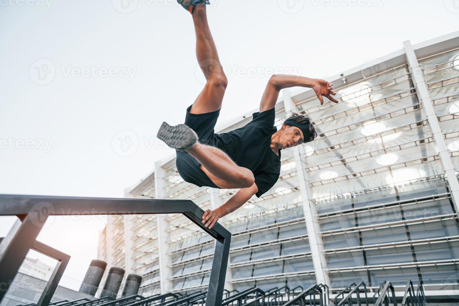 faz parkour. jovem em roupas esportivas tem treino ao ar livre durante o dia foto