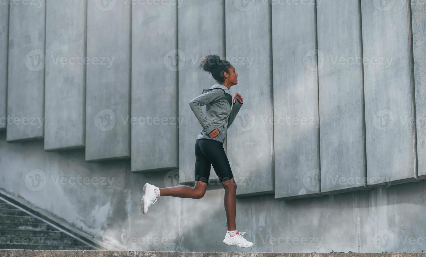 concepção de esporte. jovem afro-americana em roupas esportivas tem treino ao ar livre durante o dia foto