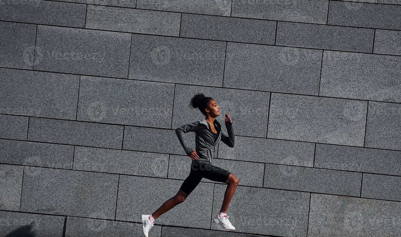 corredor ativo. jovem afro-americana em roupas esportivas tem treino ao ar livre durante o dia foto