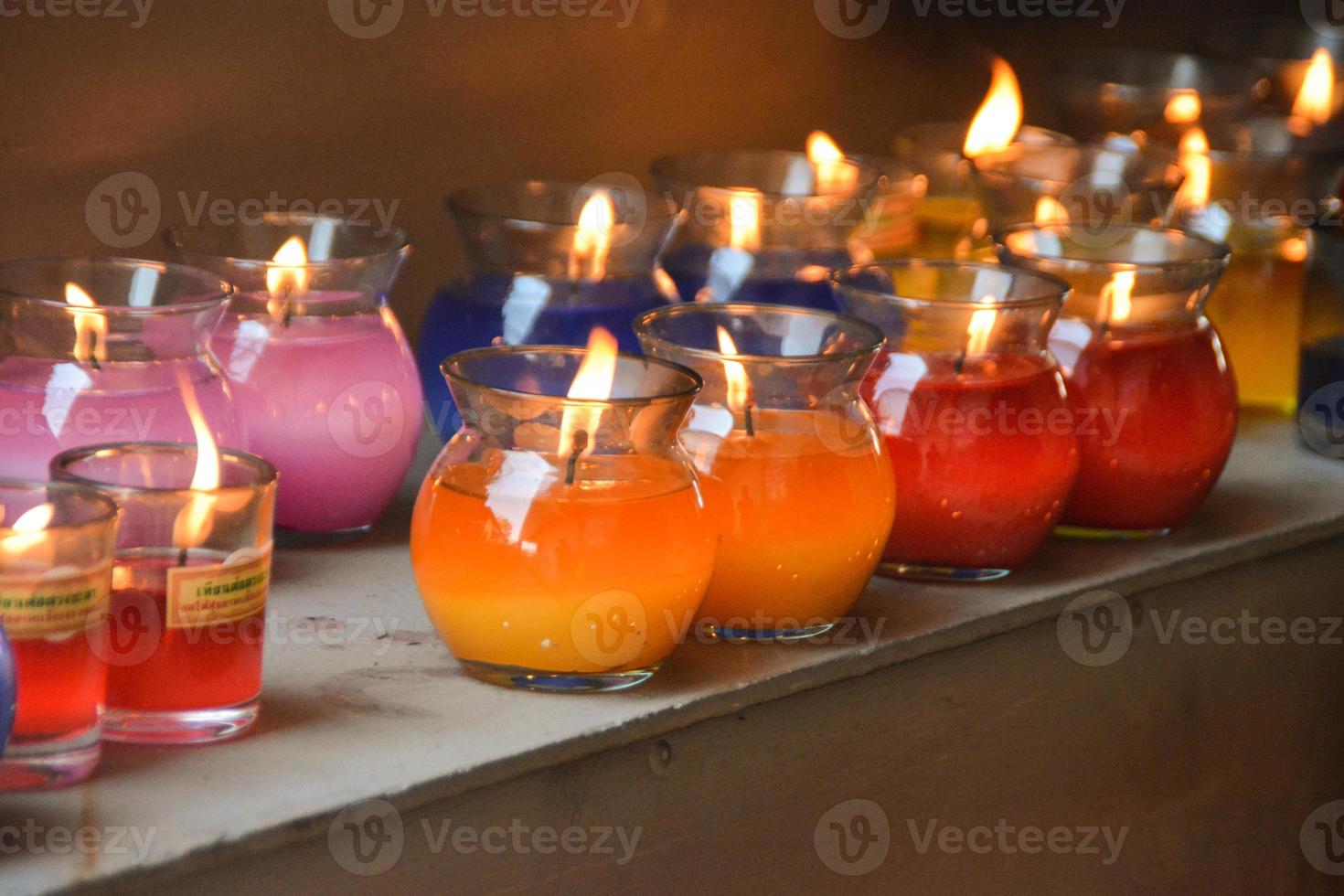 queimando velas de cores diferentes em todas as jarras de vidro do santuário. foto