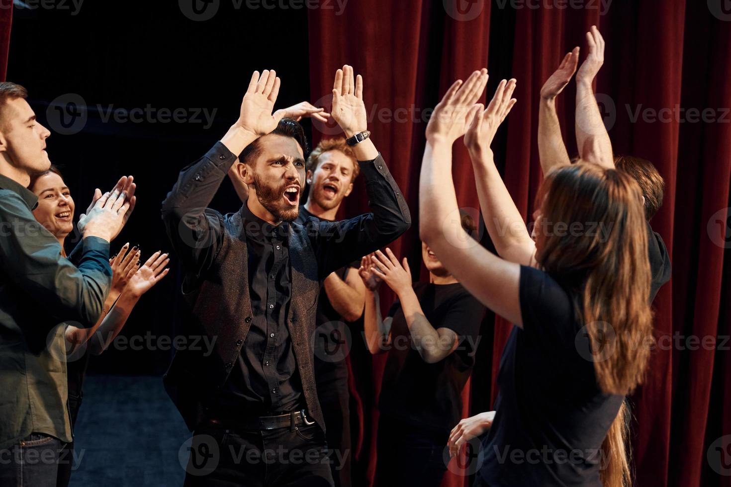 dando mais cinco, comemorando o sucesso. grupo de atores em roupas de cor escura no ensaio no teatro foto