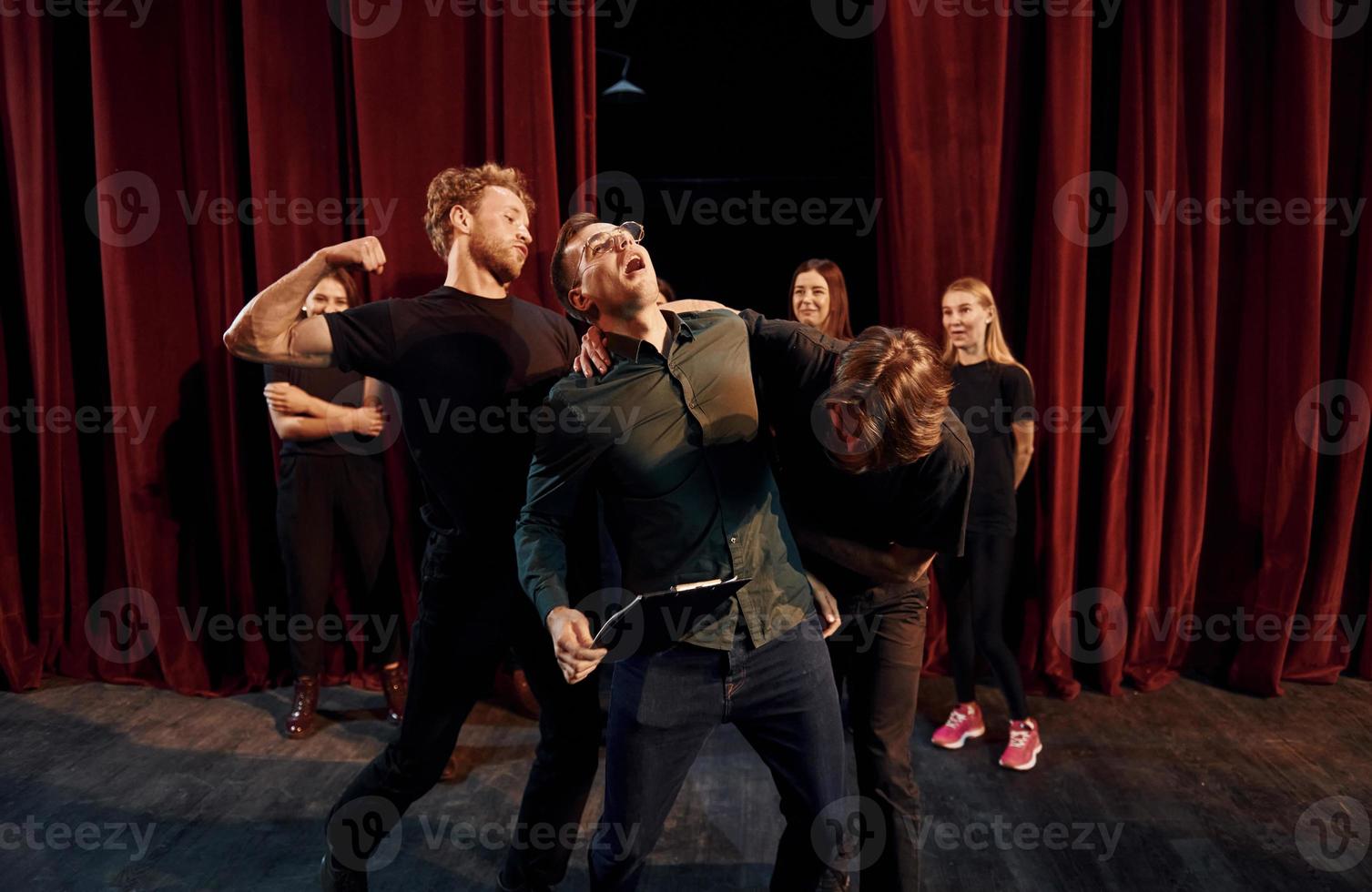 cena de luta. grupo de atores em roupas de cor escura no ensaio no teatro foto