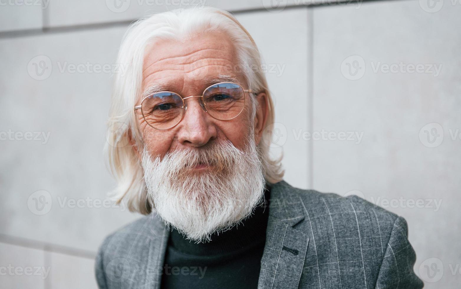 retrato de empresário sênior em roupas formais, com cabelos grisalhos e barba que está ao ar livre foto