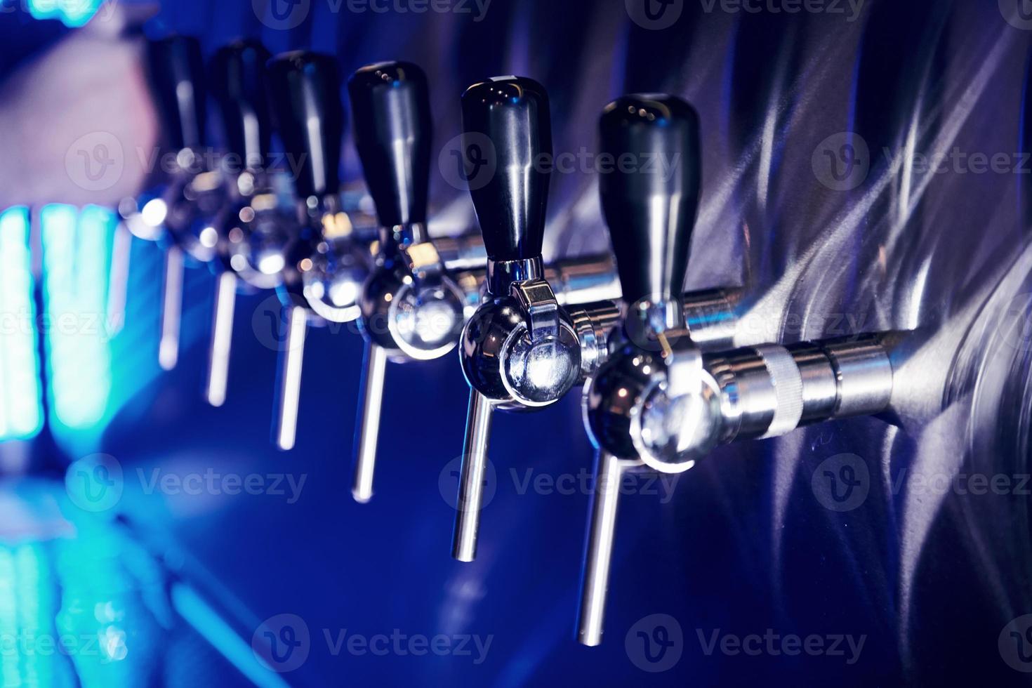 close-up vista das torneiras de cerveja em um pub. iluminação azul artificial foto