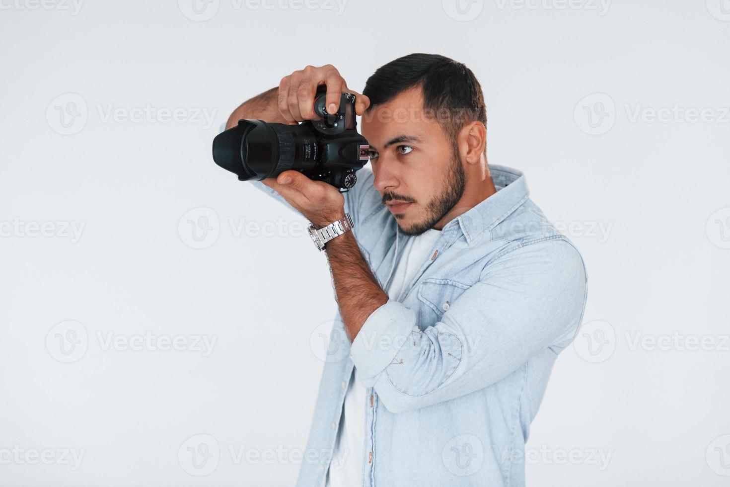 com câmera profissional. jovem bonito em pé dentro de casa contra um fundo branco foto