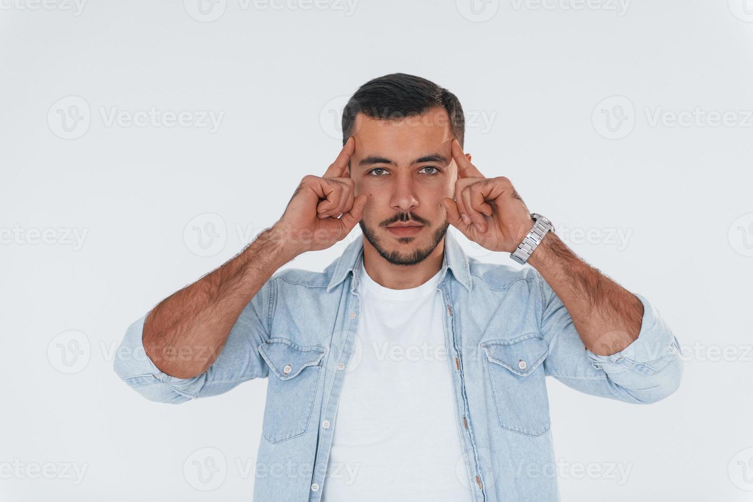 jovem bonito em pé dentro de casa contra um fundo branco foto