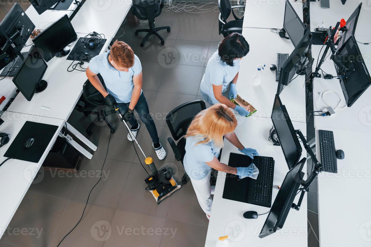 vista do topo. grupo de trabalhadores limpa escritório moderno juntos durante o dia foto