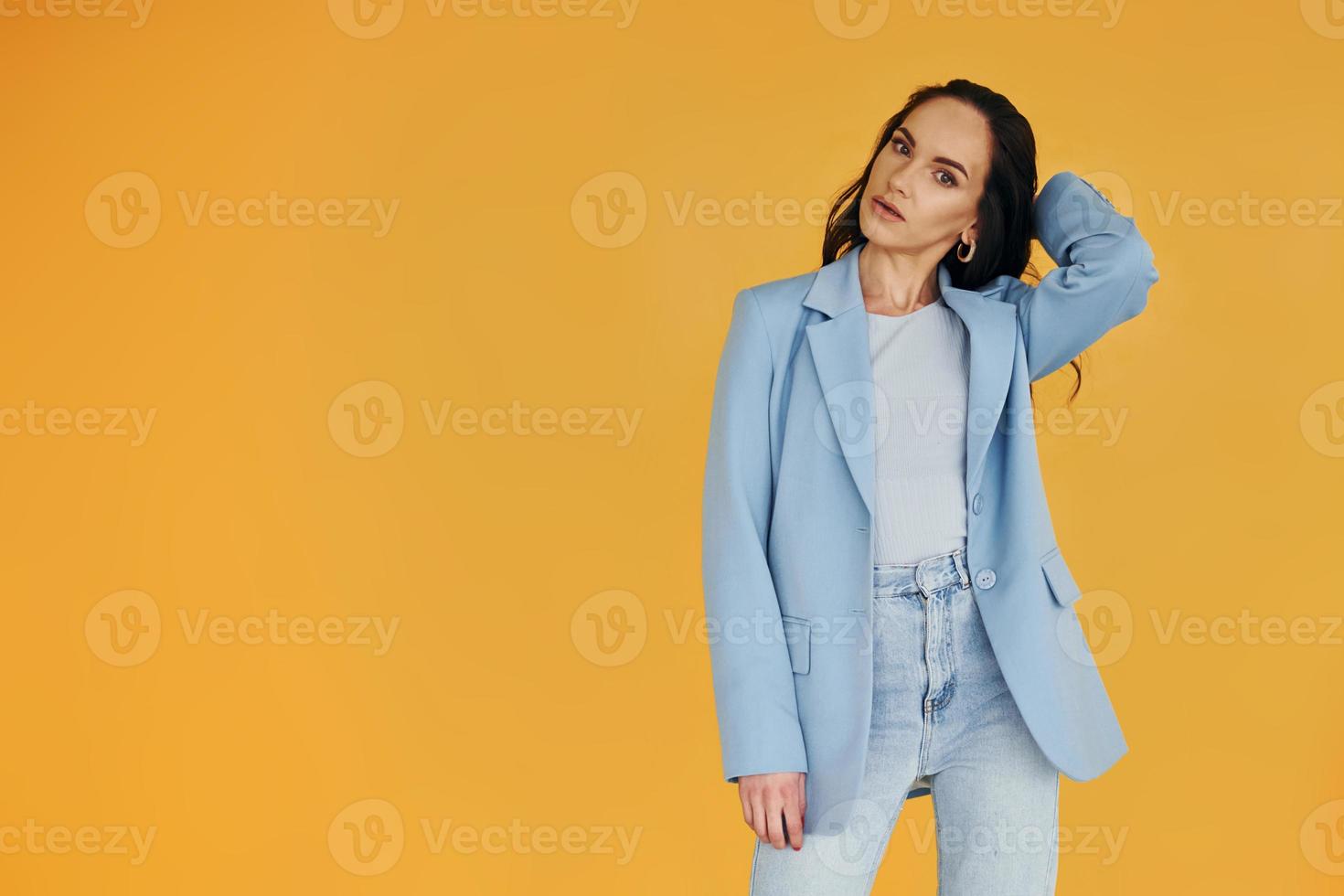 contra um fundo amarelo. mulher europeia em roupas elegantes da moda está posando dentro de casa foto