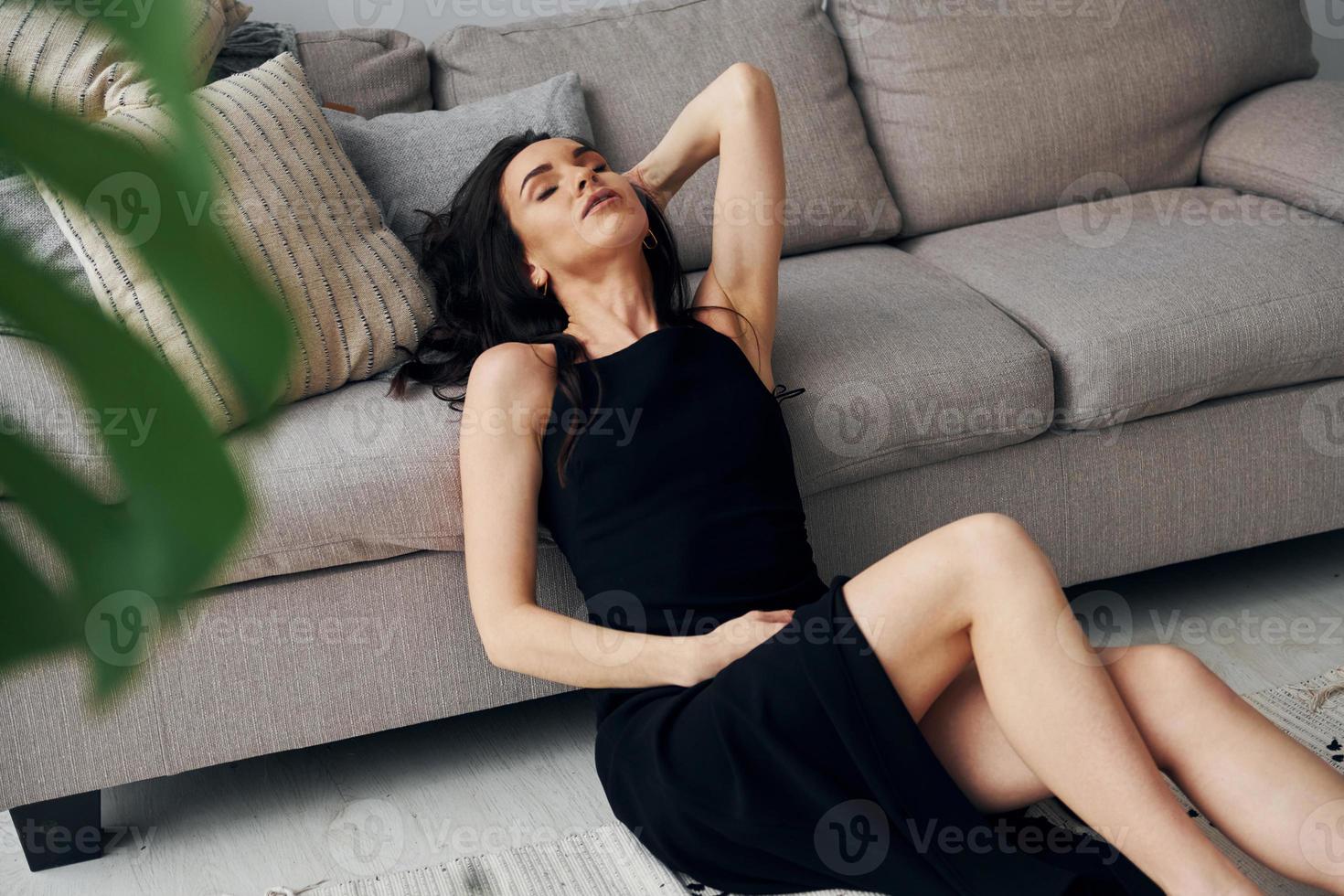 senta no chão perto da cama. mulher europeia em roupas elegantes da moda está posando dentro de casa foto