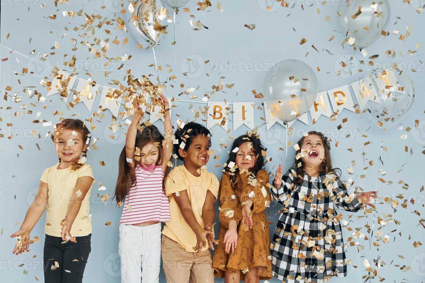 balões e confetes. as crianças comemorando a festa de aniversário dentro de casa se divertem juntas foto