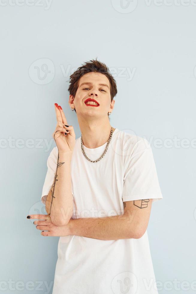 jovem gay está de pé no estúdio e posando para uma câmera. mostra gestos foto