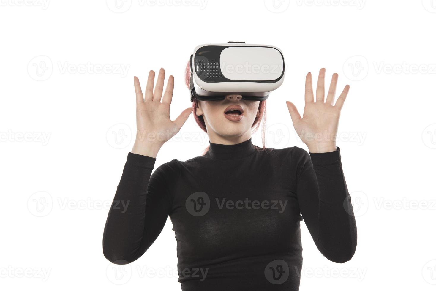 mulher muito bonita animada no fone de ouvido vr olhando para cima e tentando tocar objetos na realidade virtual foto