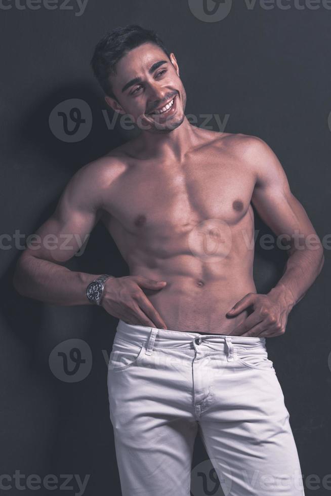 belo modelo masculino árabe com corpo perfeito posando no estúdio. retrato de um modelo masculino atlético posando em fundo escuro no estúdio. conceito de moda. foto