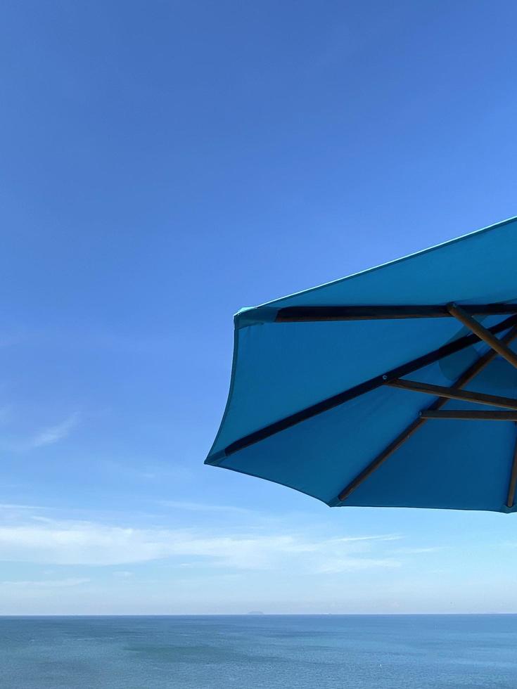 guarda-chuva de praia azul no fundo do céu azul de verão foto
