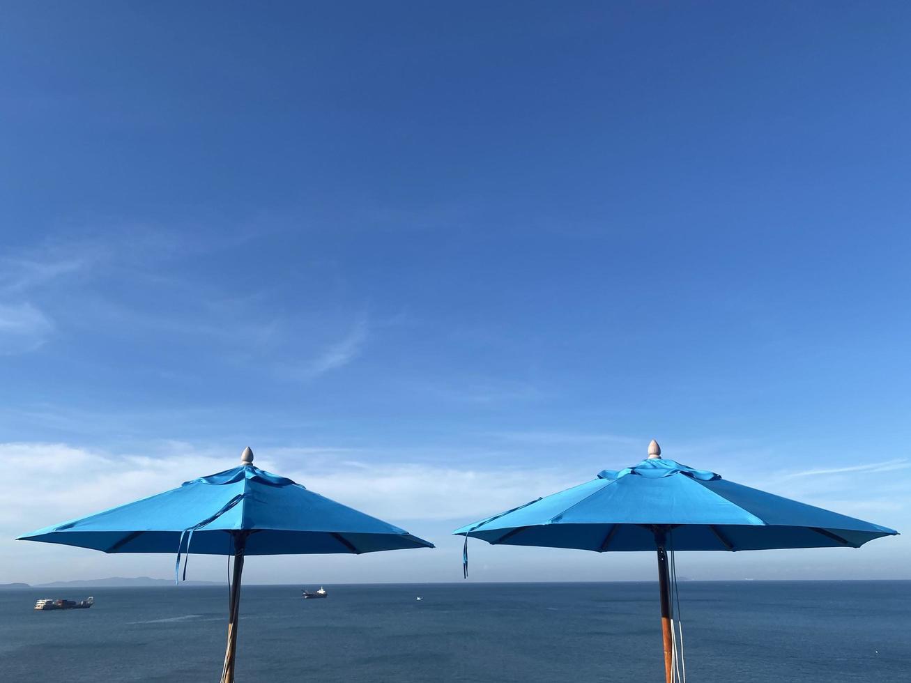 guarda-chuva de praia azul no fundo do céu azul de verão foto