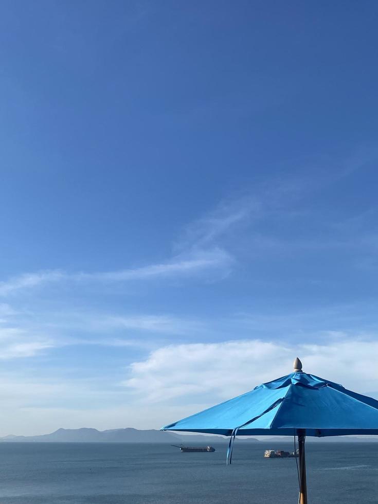 guarda-chuva de praia azul no fundo do céu azul de verão foto
