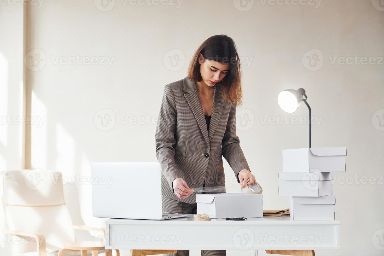 pedidos de embalagem nas caixas brancas. jovem mulher com roupas formais está dentro de casa. concepção de estilo foto