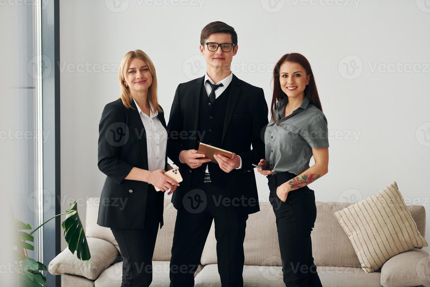 rapaz e duas mulheres em roupas oficiais formais juntos dentro de casa foto