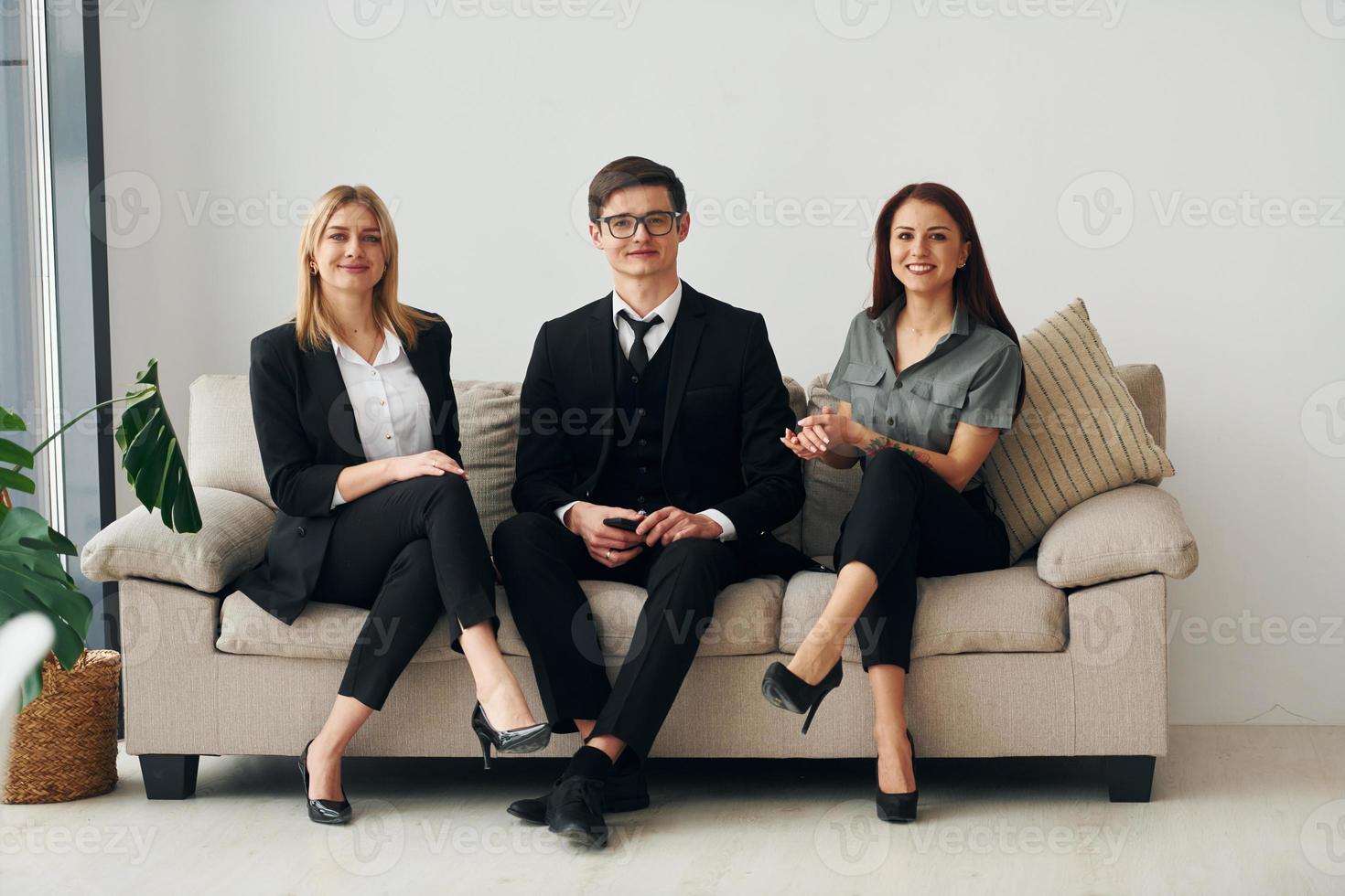 rapaz e duas mulheres em roupas oficiais formais juntos dentro de casa foto