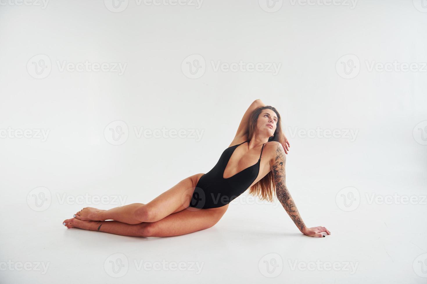 deitado no chão. bela mulher desportiva sedutora com corpo sexy está posando no estúdio foto