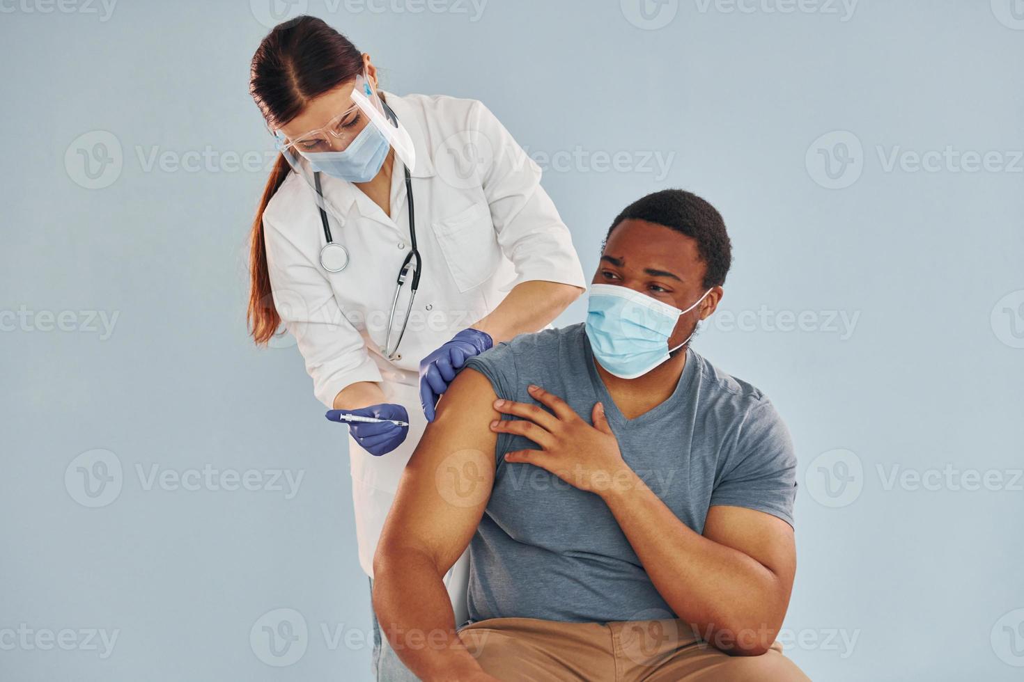 médica dando injeção para homem afro-americano no hospital foto