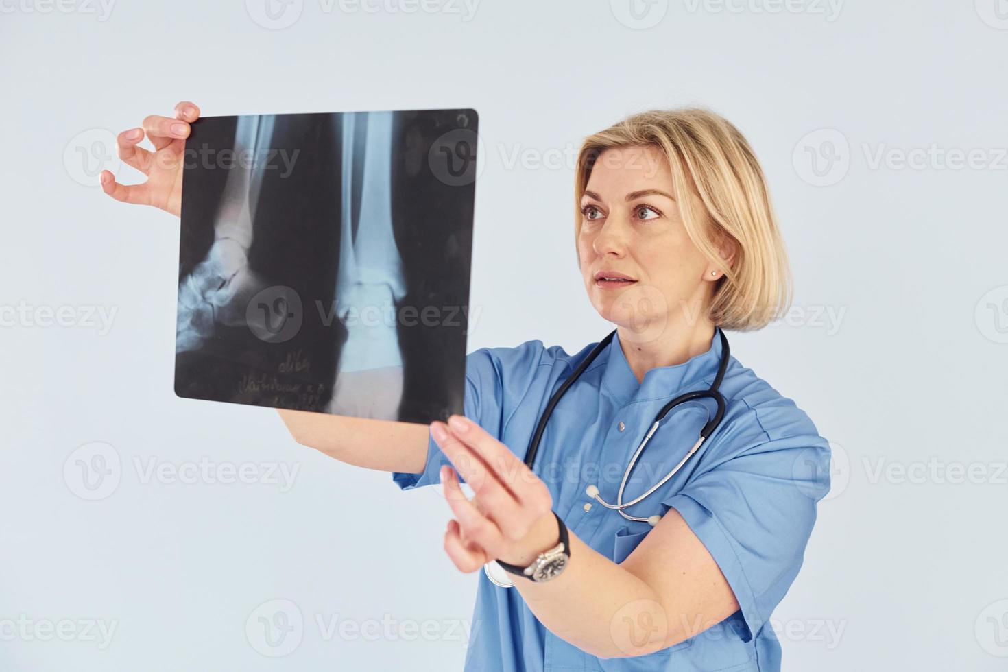 mantém o raio-x. médica profissional de meia-idade de uniforme e com estetoscópio foto