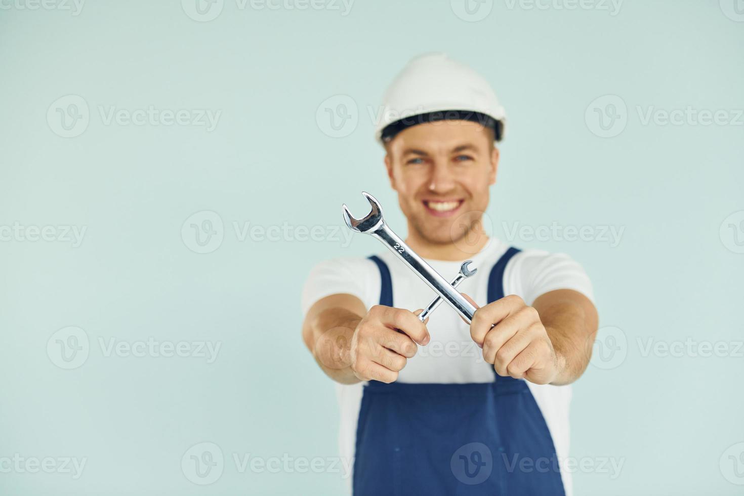 trabalhador de uniforme e capacete em pé no estúdio com equipamento foto