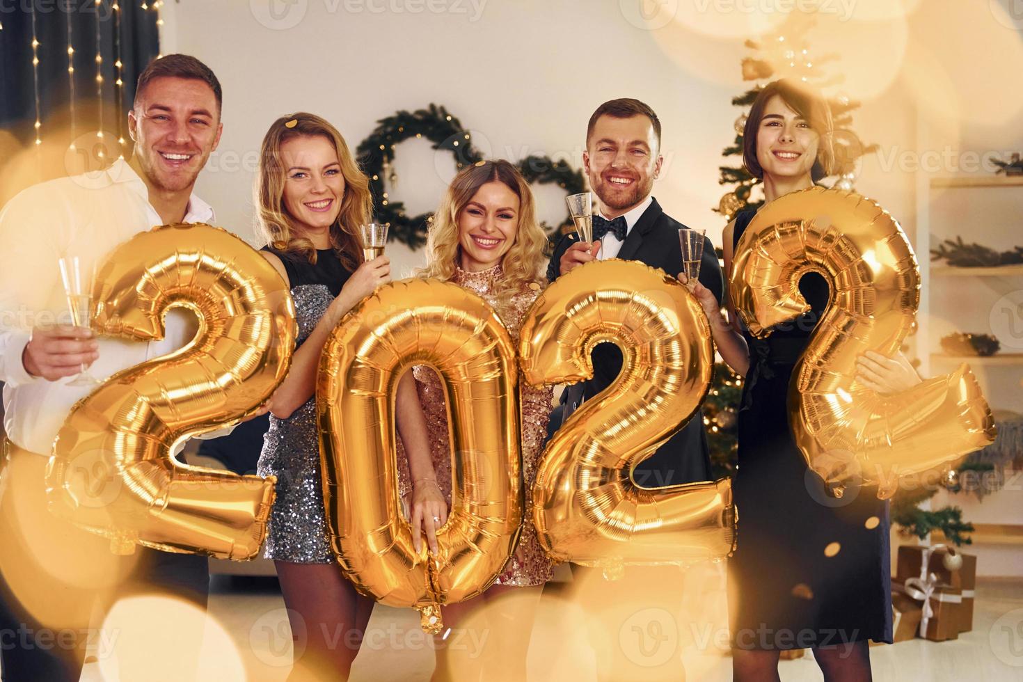 2022 ano. grupo de pessoas tem uma festa de ano novo dentro de casa juntos foto