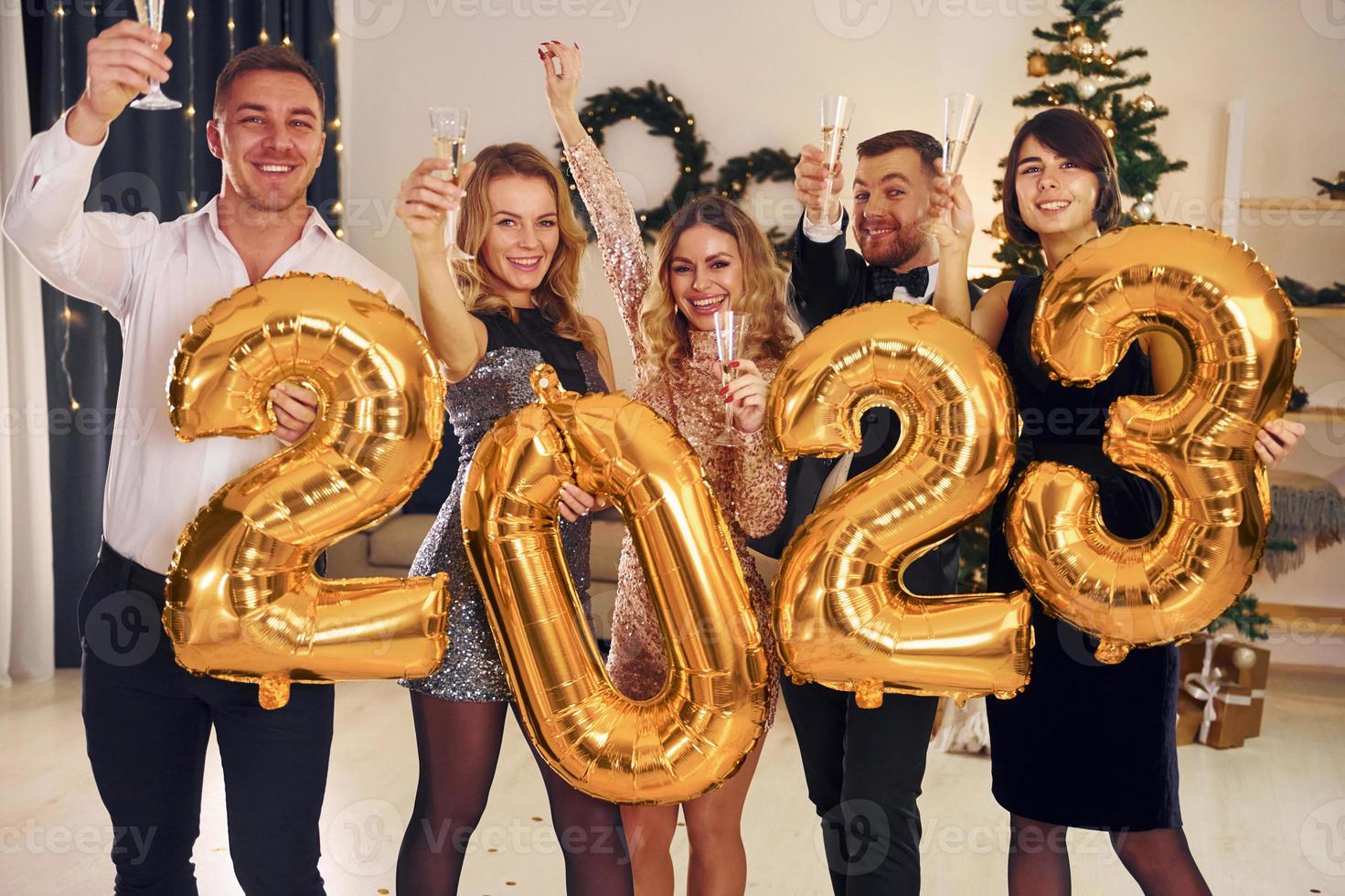2023 balões nas mãos. grupo de pessoas tem uma festa de ano novo dentro de casa juntos foto