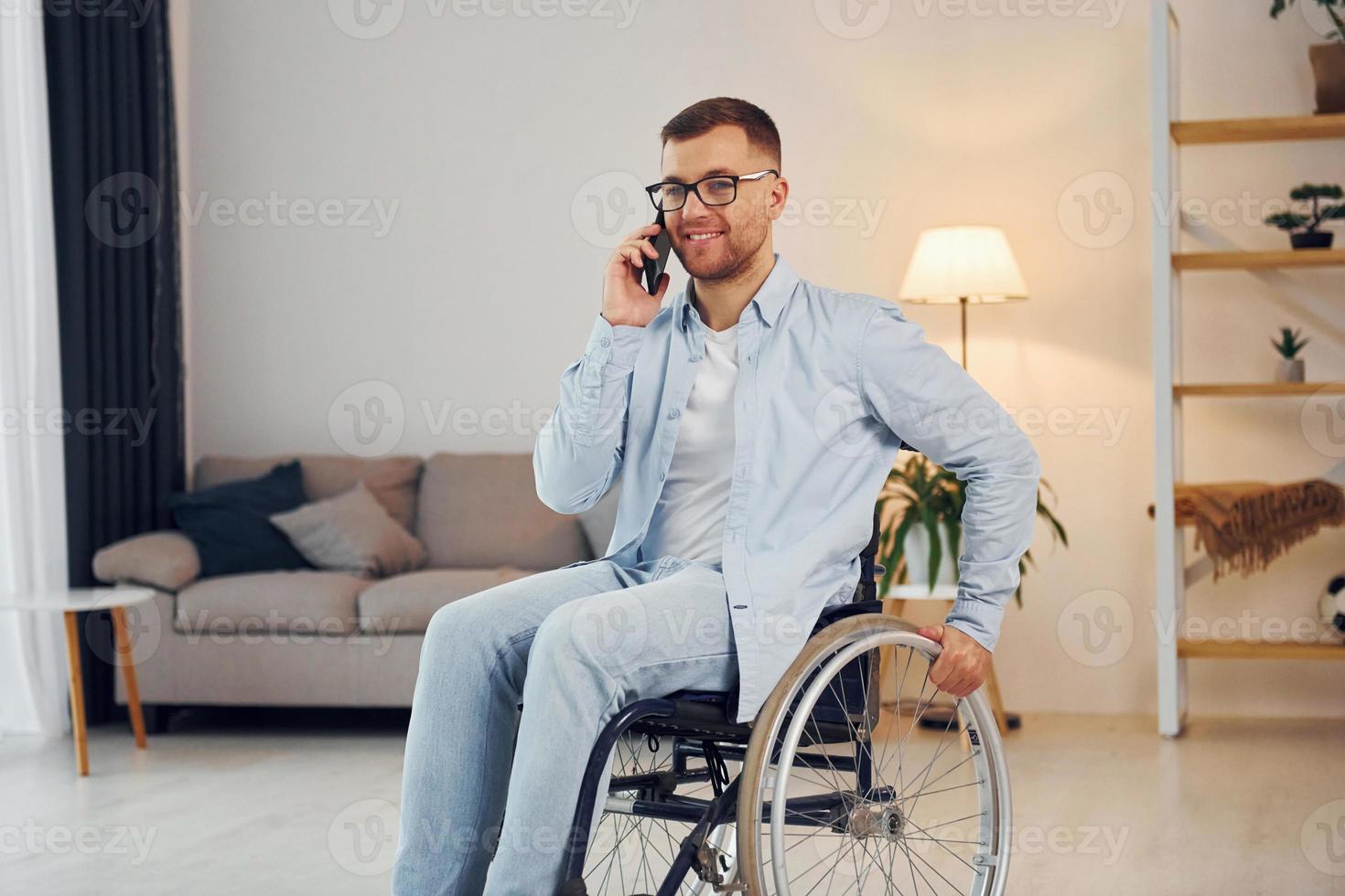falando por telefone. homem com deficiência em cadeira de rodas está em casa foto