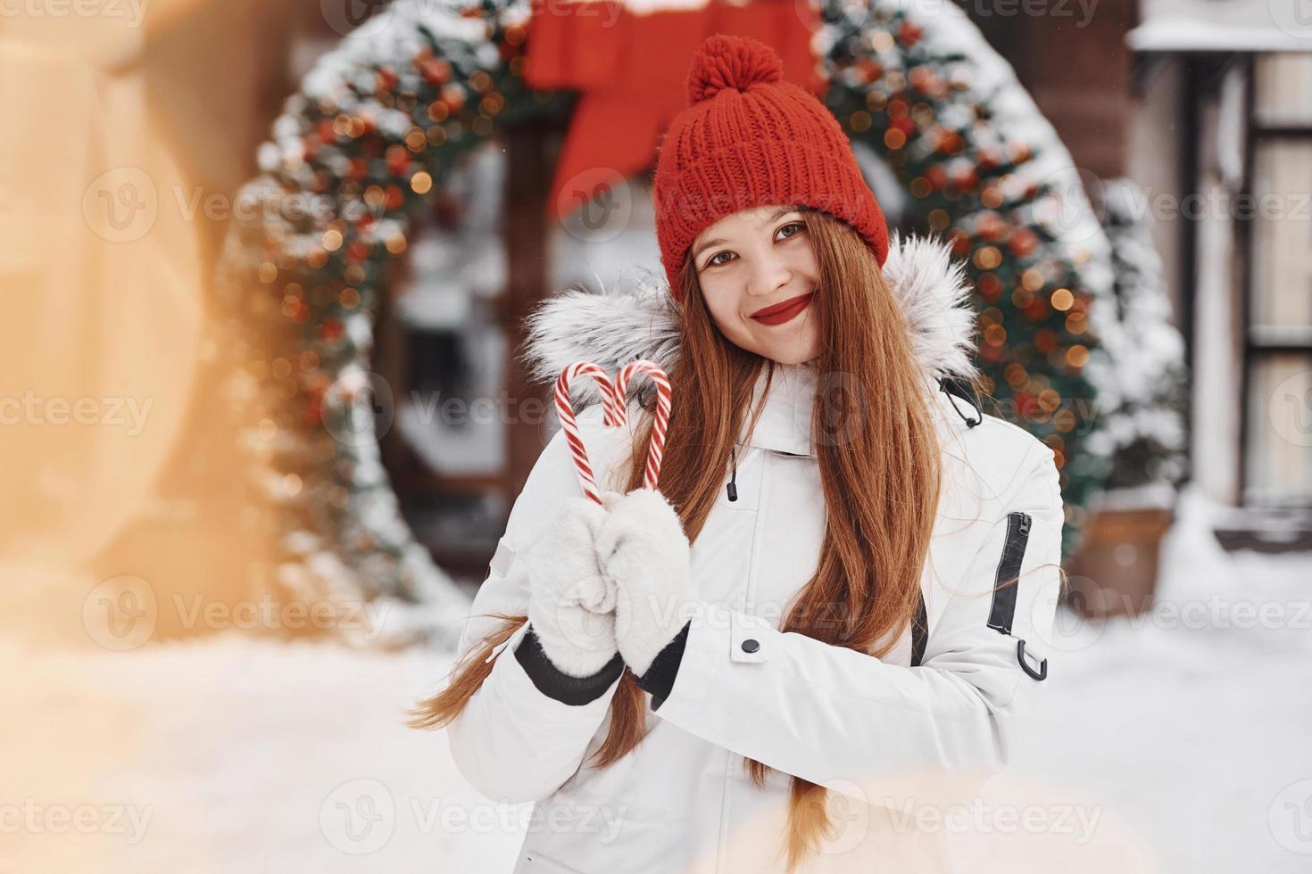 segurando doces. mulher jovem feliz em pé ao ar livre e comemorando as férias de natal foto