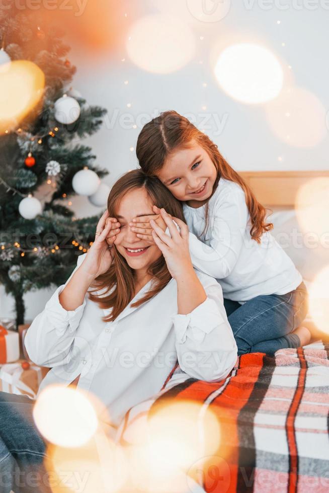 mãe com sua filha está se divertindo dentro de casa na cama foto