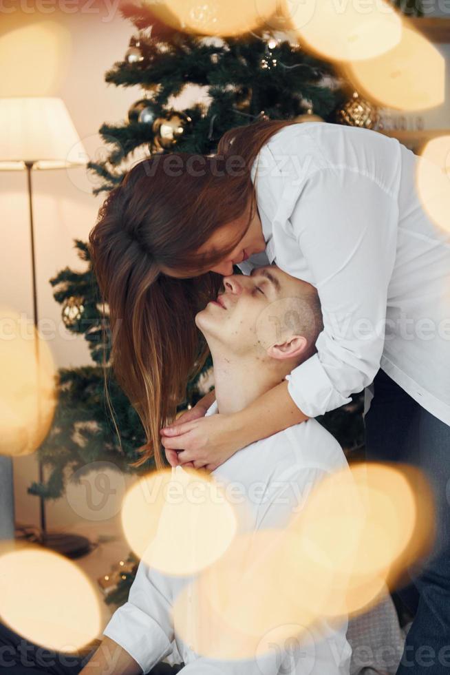 abraçando um ao outro. lindo casal comemorando feriados juntos dentro de casa foto