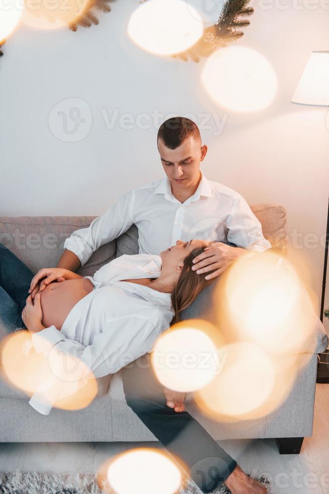 mulher está grávida. lindo casal comemorando feriados juntos dentro de casa foto